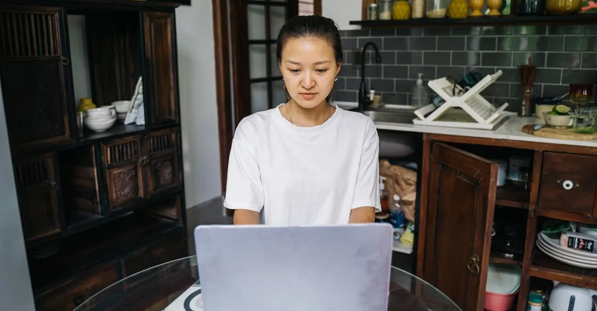 Woman concentrating on a telehealth session at her kitchen laptop