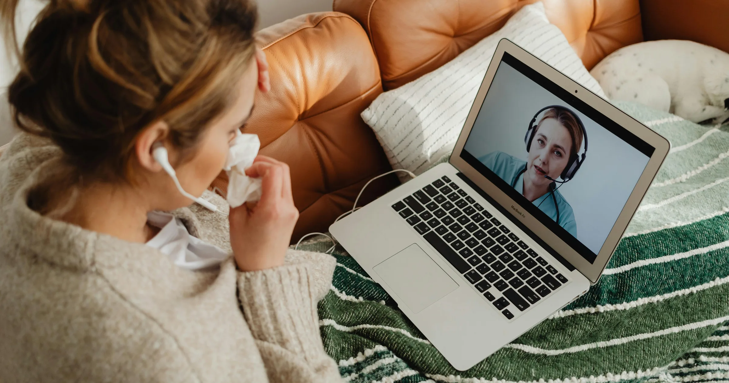 Woman having an online medical consultation on a laptop from her home sofa