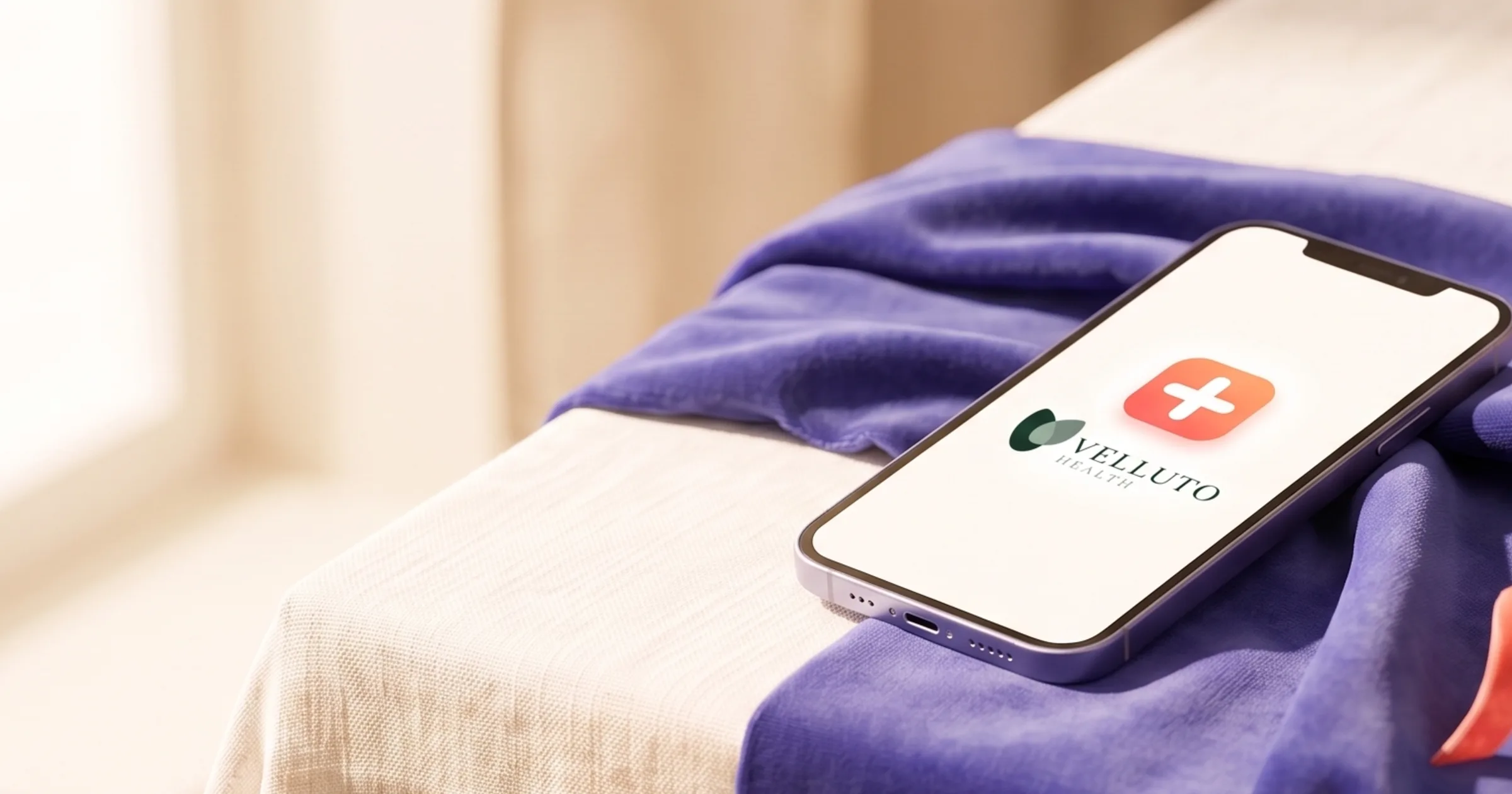 A smartphone showing the MySpecialistGP and Velluto Health logos on a welcome screen, resting on indigo velvet over cream linen, soft natural light